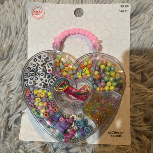 multicolor beads and strings in a heart-shaped plastic package shaped like a purse with a pink handle.